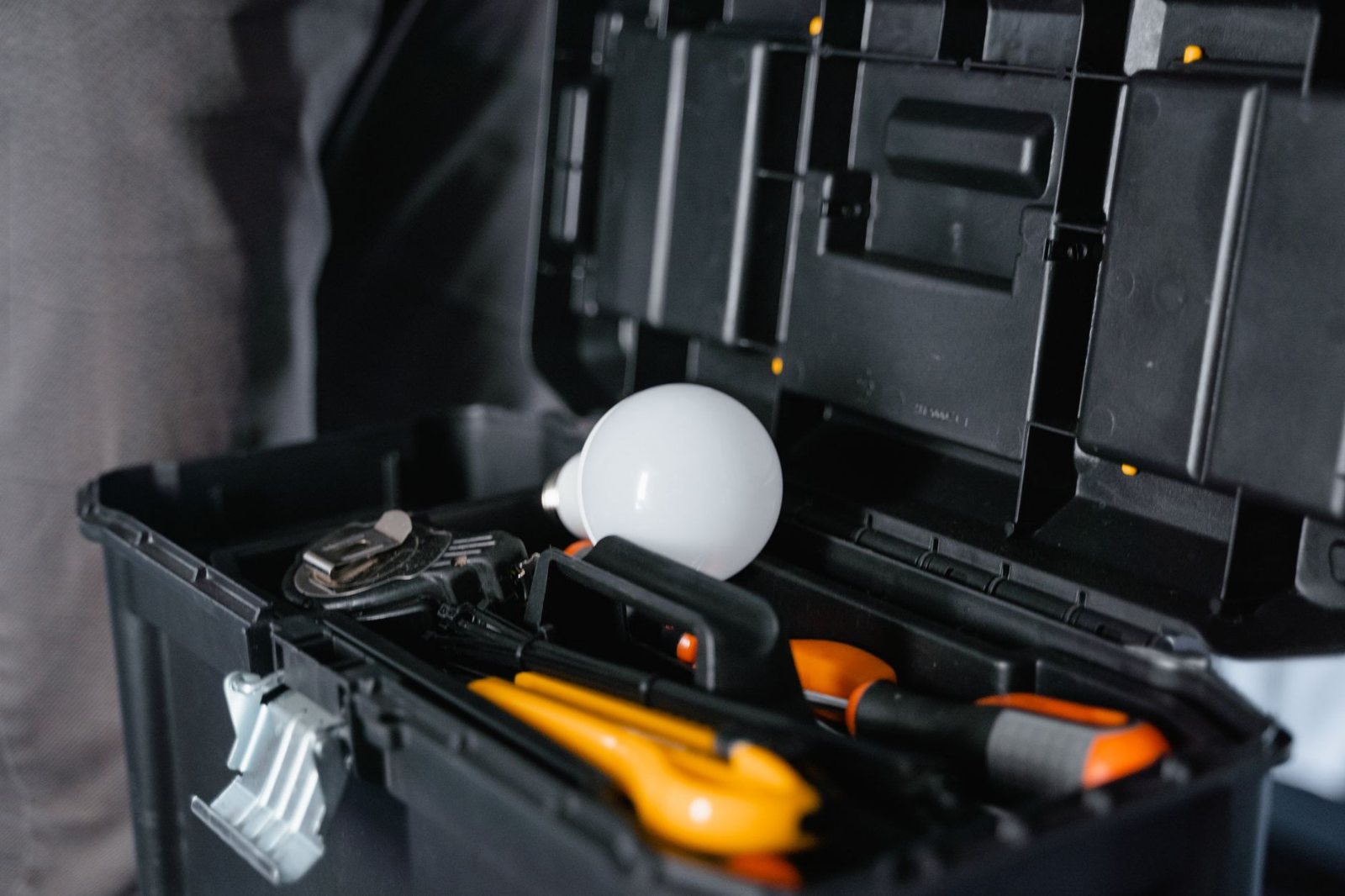 An electrician's working kit staged on a drop cloth before the first cut: hard tool cases open, hand tools and a cordless drill laid out as they were actually set down, floor protection under them.