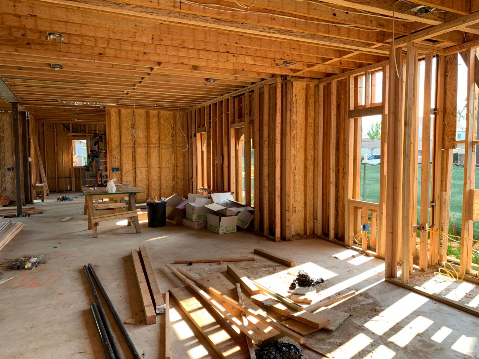 A new-construction rough-in: open stud bays with neatly stapled runs of romex and mounted device boxes, drywall not yet up, daylight through unglazed window openings. No people in frame, but the work is clearly half-done and recent.